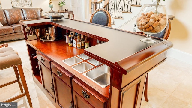 bar featuring stairs, light tile patterned floors, a sink, and baseboards