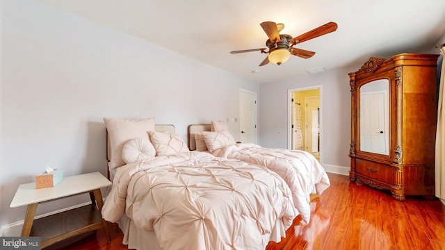 bedroom with ensuite bathroom, wood finished floors, a ceiling fan, and baseboards