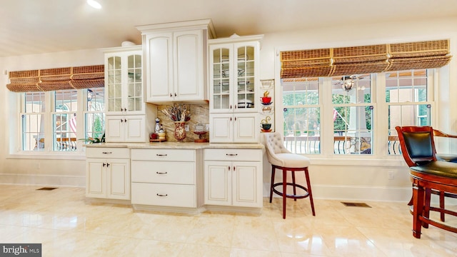 kitchen with visible vents, light countertops, glass insert cabinets, and baseboards