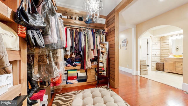 spacious closet with arched walkways and wood finished floors