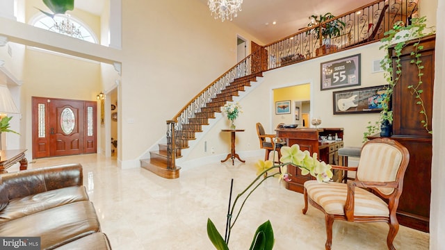 entryway with stairway, baseboards, a high ceiling, and a chandelier