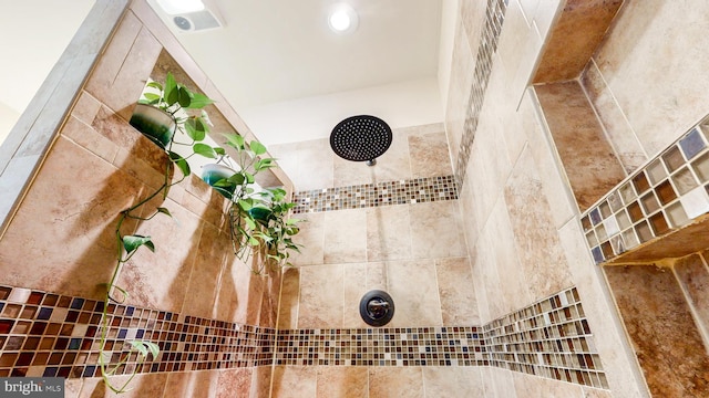 room details featuring a tile shower and visible vents