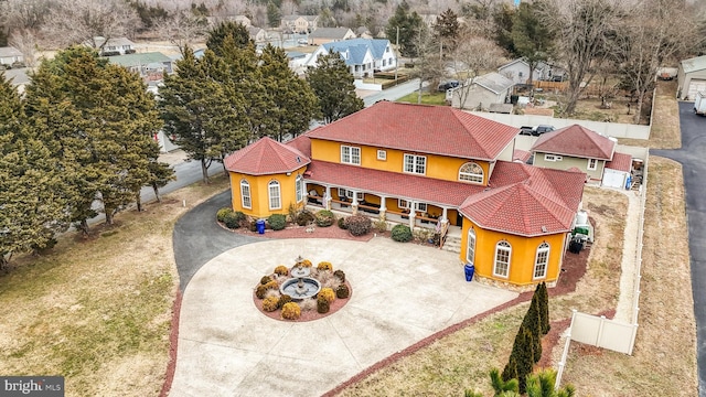 view of front of house featuring driveway, stucco siding, a porch, and a tiled roof