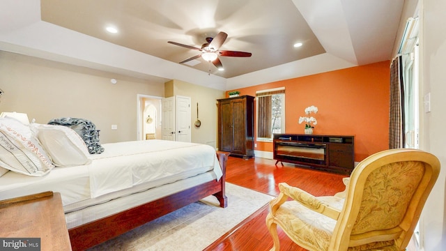 bedroom featuring ceiling fan, a raised ceiling, wood finished floors, and recessed lighting