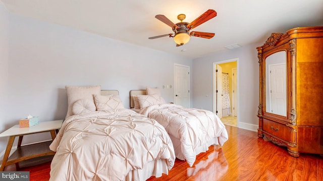 bedroom featuring light wood finished floors, baseboards, visible vents, and a ceiling fan