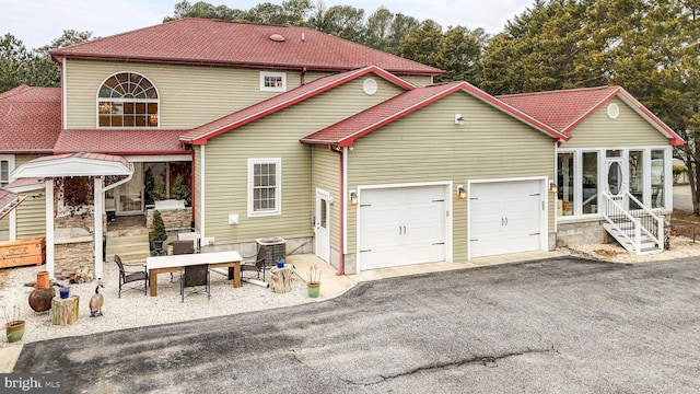 view of front facade with entry steps, aphalt driveway, an attached garage, and cooling unit