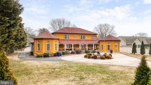 back of property featuring curved driveway, a lawn, and stucco siding