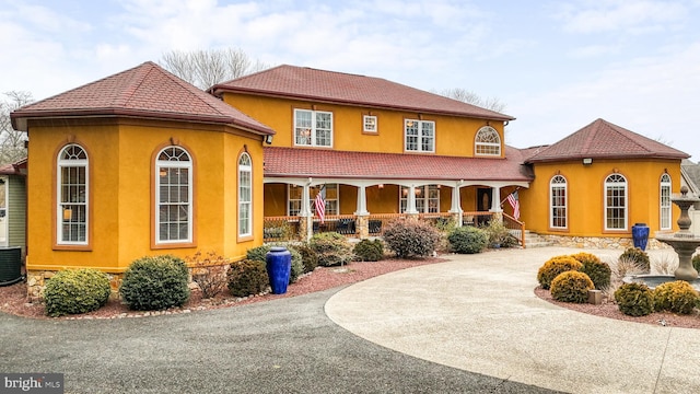 view of front facade with driveway, covered porch, and stucco siding