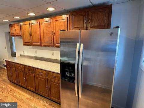 kitchen with a paneled ceiling, stainless steel fridge, and light hardwood / wood-style floors