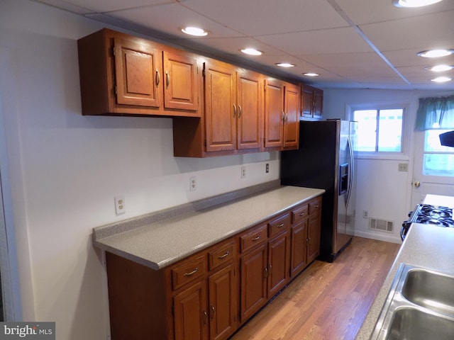 kitchen featuring sink, light wood-type flooring, stainless steel fridge, white range with gas cooktop, and a drop ceiling