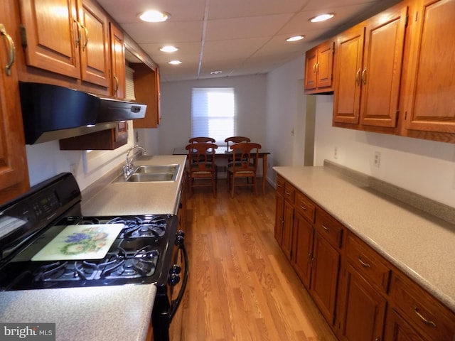 kitchen with a paneled ceiling, sink, black range with gas stovetop, exhaust hood, and light hardwood / wood-style floors