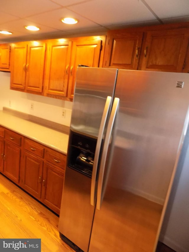 kitchen with a paneled ceiling, stainless steel fridge with ice dispenser, and light wood-type flooring