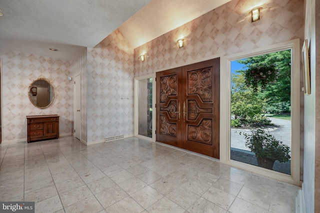 entryway with wallpapered walls, visible vents, and baseboards