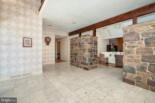 living room with wallpapered walls, visible vents, baseboards, and a textured ceiling