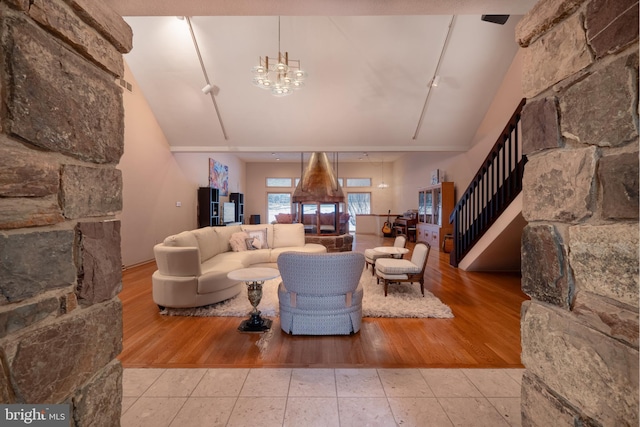 living room featuring high vaulted ceiling, wood finished floors, stairway, and an inviting chandelier