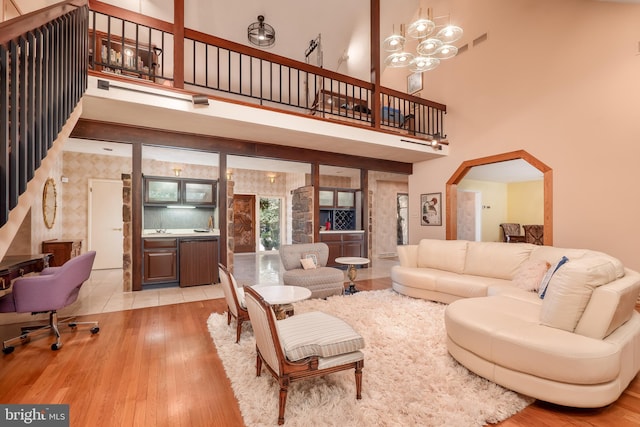 living room with a towering ceiling, an inviting chandelier, arched walkways, and wood finished floors