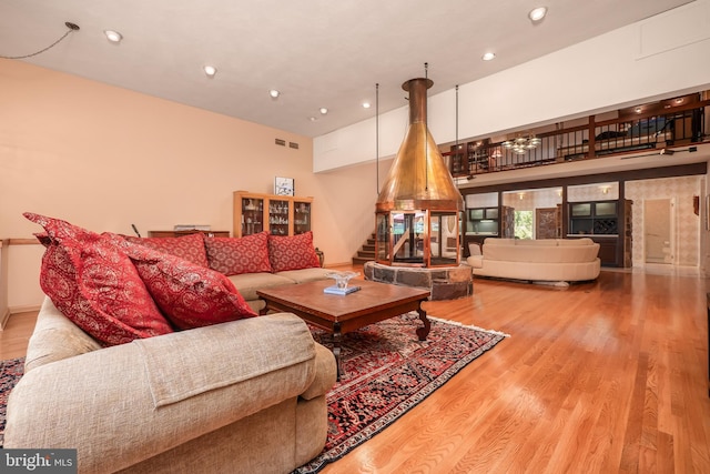 living area with visible vents, a towering ceiling, stairway, wood finished floors, and recessed lighting