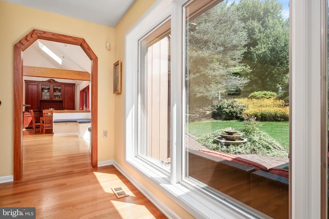 entryway featuring baseboards, lofted ceiling, visible vents, and light wood-style floors