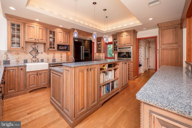 kitchen featuring open shelves, visible vents, black appliances, a raised ceiling, and a center island with sink