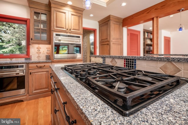 kitchen with light wood finished floors, light stone counters, gas stovetop, and oven