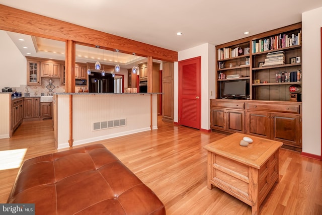 living area with a tray ceiling, visible vents, light wood-style flooring, and recessed lighting