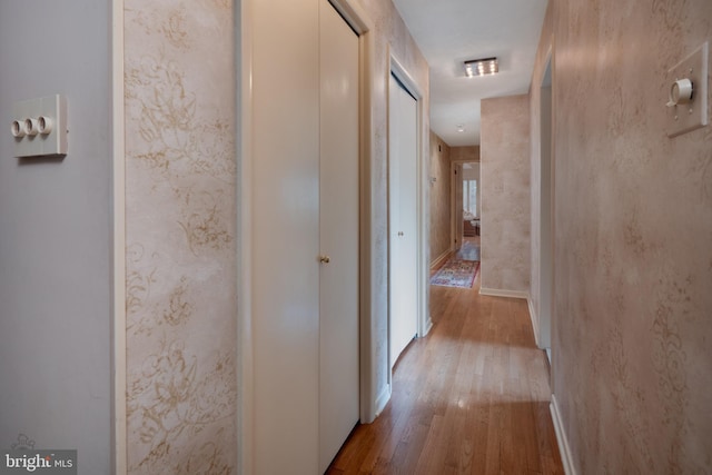 hallway featuring wood-type flooring and baseboards