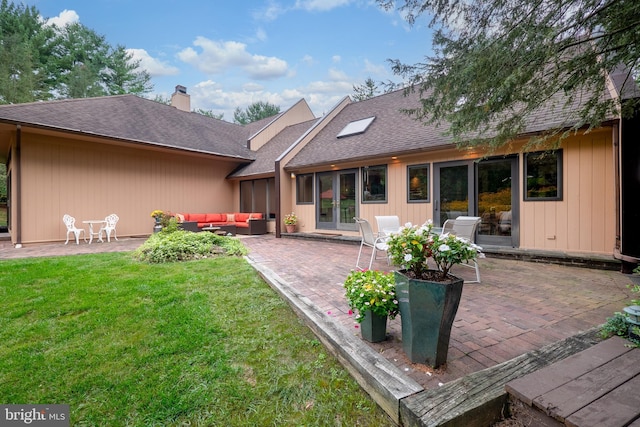 rear view of house featuring a shingled roof, a lawn, a chimney, a patio area, and outdoor lounge area