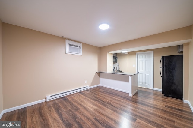 interior space with sink, dark hardwood / wood-style floors, black fridge, a baseboard radiator, and an AC wall unit