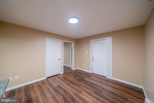 unfurnished bedroom featuring dark hardwood / wood-style flooring and baseboard heating