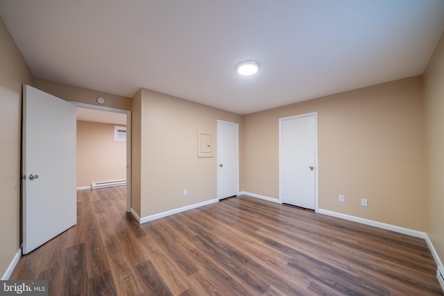 spare room with dark wood-type flooring and a baseboard radiator