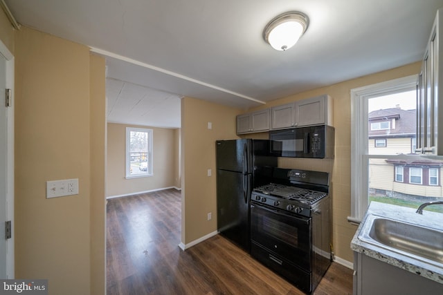 kitchen featuring dark hardwood / wood-style floors, black appliances, sink, and gray cabinetry