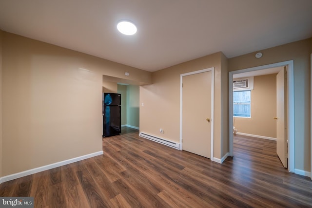 spare room featuring baseboard heating and dark hardwood / wood-style flooring