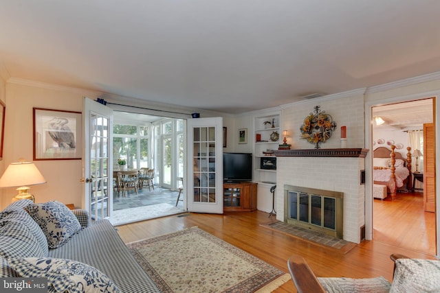 living room with hardwood / wood-style flooring, ornamental molding, a fireplace, and french doors