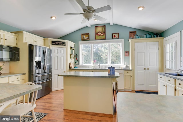 kitchen featuring a kitchen island, sink, vaulted ceiling with beams, stainless steel fridge, and light hardwood / wood-style floors