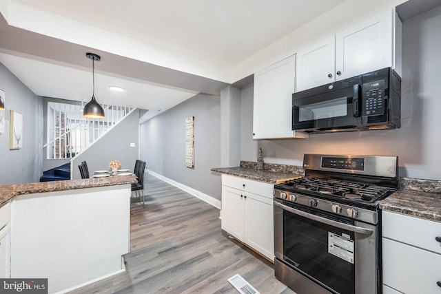 kitchen featuring white cabinetry, gas range, light wood-type flooring, and dark stone counters