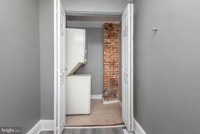 laundry area with light tile patterned floors and stacked washer / dryer