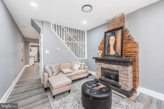 living room with wood-type flooring and a stone fireplace