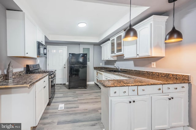 kitchen featuring sink, white cabinetry, black appliances, decorative light fixtures, and dark stone counters