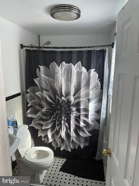 bathroom with toilet, tile walls, tile patterned floors, and walk in shower