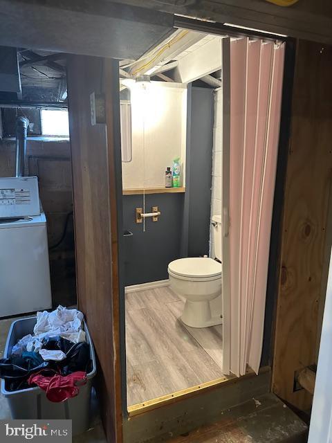 bathroom with washer / clothes dryer, wood-type flooring, and toilet