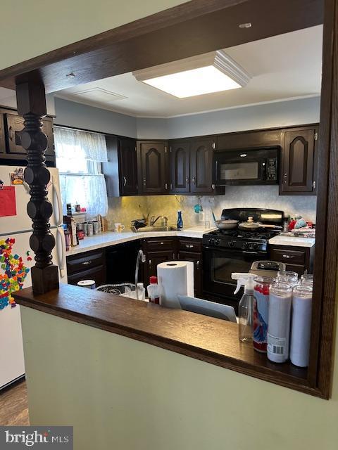 kitchen featuring tasteful backsplash, sink, dark brown cabinetry, and black appliances