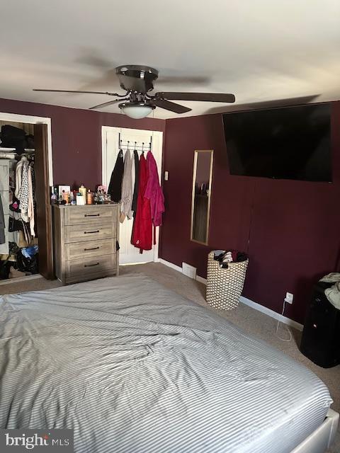 carpeted bedroom featuring ceiling fan and a closet