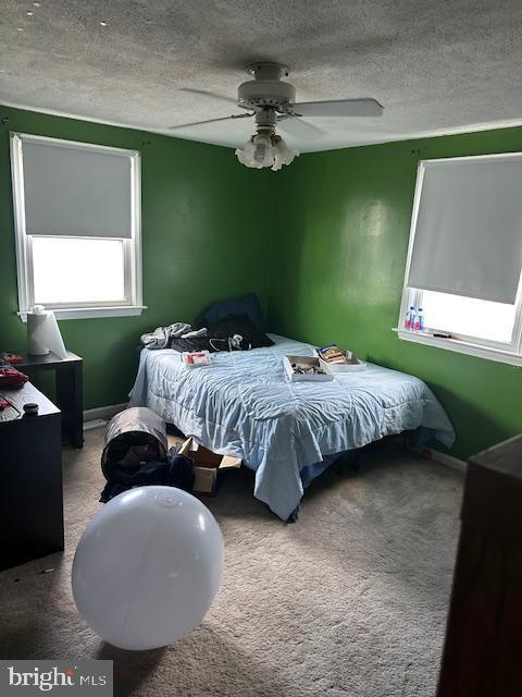 bedroom with ceiling fan, carpet floors, and a textured ceiling