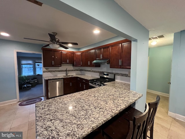 kitchen featuring sink, a breakfast bar area, appliances with stainless steel finishes, kitchen peninsula, and light stone countertops