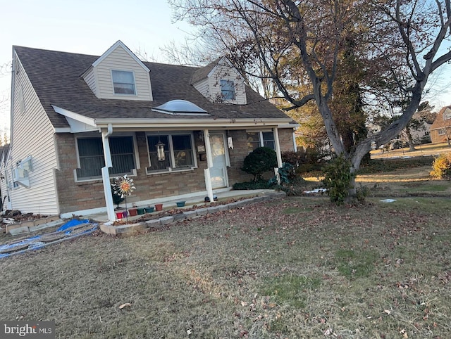 cape cod house featuring covered porch and a front yard