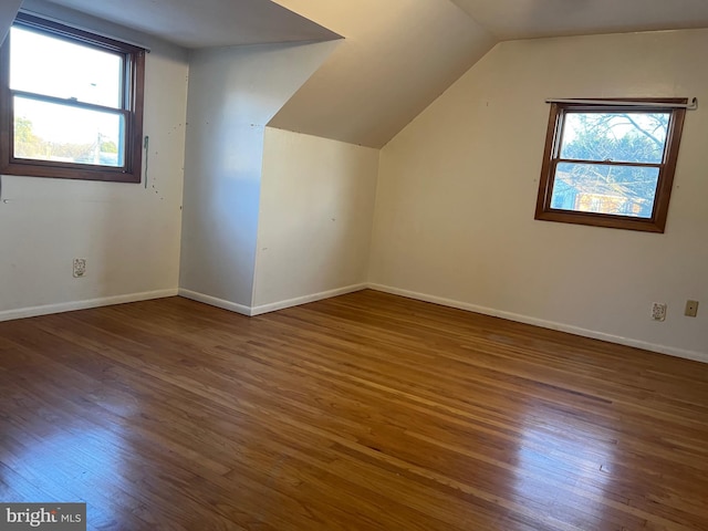 additional living space with dark wood-type flooring and vaulted ceiling