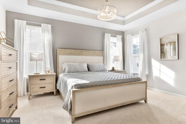 carpeted bedroom with an inviting chandelier, ornamental molding, and a raised ceiling