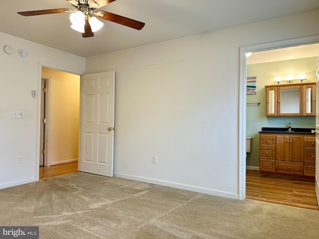 unfurnished bedroom with a ceiling fan, carpet flooring, a sink, and baseboards