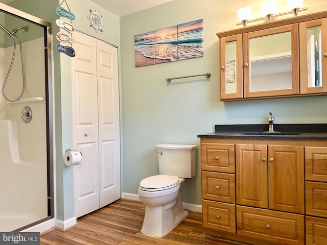 bathroom with vanity, a stall shower, wood finished floors, and toilet