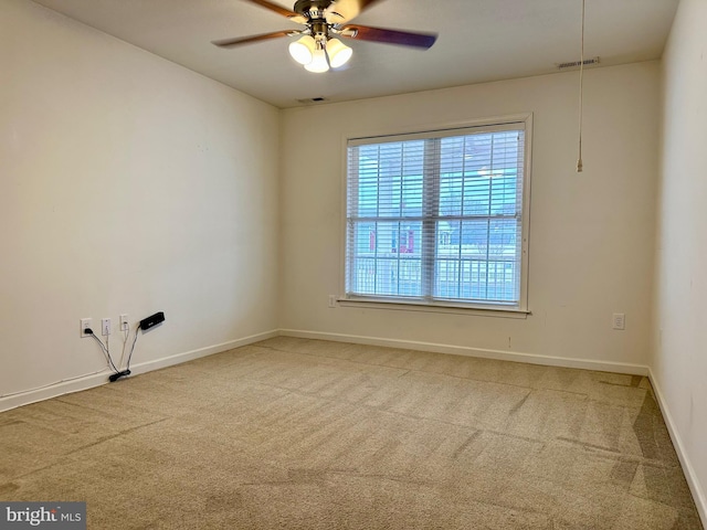 carpeted spare room with ceiling fan, visible vents, and baseboards